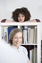Porträt einer lächelnden jungen Frau mit Kollegen im Büro - FKF001311