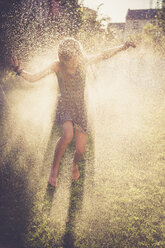 Mädchen hat Spaß mit spritzendem Wasser im Garten - SARF002038