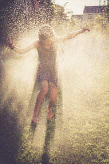 Mädchen hat Spaß mit spritzendem Wasser im Garten - SARF002038