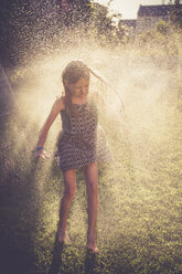 Mädchen hat Spaß mit spritzendem Wasser im Garten - SARF002060