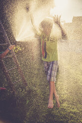 Junge und Mädchen haben Spaß mit spritzendem Wasser im Garten - SARF002061