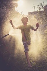 Boy having fun with splashing water in the garden - SARF002036