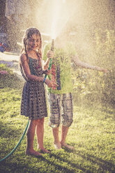 Zwei Kinder planschen mit Wasser im Garten - SARF002035