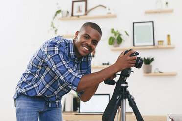 Porträt eines lächelnden jungen Mannes bei der Arbeit in seinem Fotostudio - EBSF000766