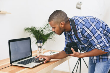 Junger Mann arbeitet mit Laptop in seinem Fotostudio - EBSF000774