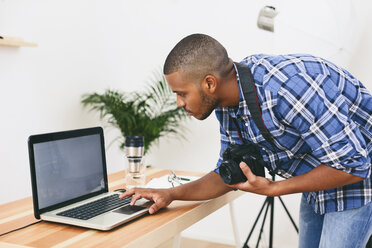 Young man working with laptop in his photographic studio - EBSF000774