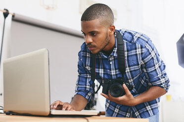 Junger Mann arbeitet mit Laptop in seinem Fotostudio - EBSF000775