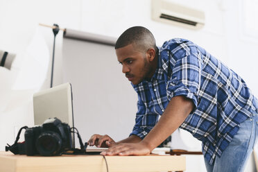 Junger Mann arbeitet mit Laptop in seinem Fotostudio - EBSF000795