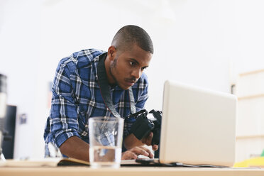 Junger Mann arbeitet mit Laptop in seinem Fotostudio - EBSF000777