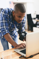 Junger Mann arbeitet mit Laptop in seinem Fotostudio - EBSF000778
