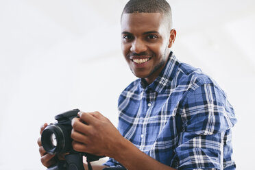 Porträt eines lächelnden jungen Mannes in seinem Fotostudio - EBSF000783