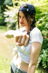 Porträt einer jungen Frau mit Baseballmütze und Faust - MGOF000321