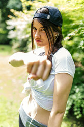 Portrait of young woman with baseball cap showing fist - MGOF000321