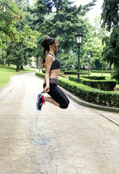 Spain, Oviedo, young woman jumping rope in the park - MGOF000319
