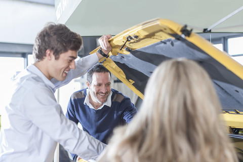 Car dealer showing new car to couple stock photo