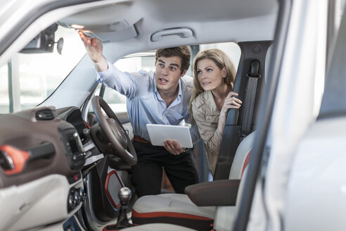 Car dealer showing new car to woman - ZEF006895