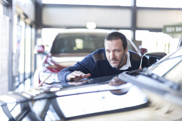 Man examining new car at car dealership - ZEF006897