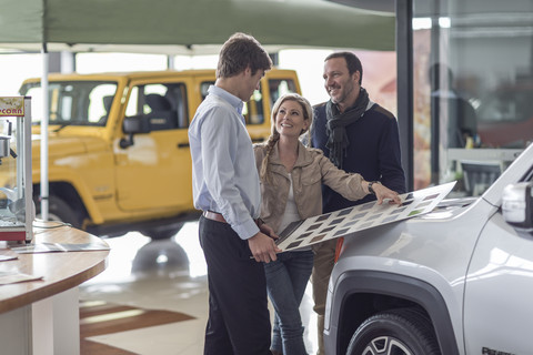 Pärchen wählt im Autohaus ein Farbmuster aus, lizenzfreies Stockfoto