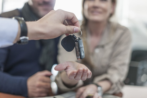 Autohändler übergibt Schlüssel an Kunden, lizenzfreies Stockfoto