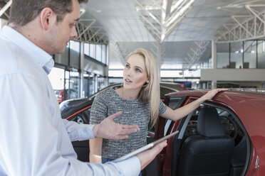 Autohändler erklärt einer jungen Frau ein neues Auto - ZEF006930