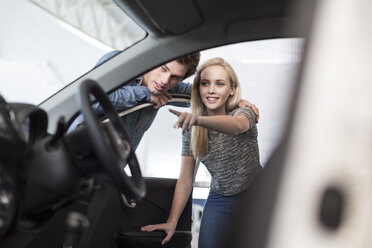 Young couple examining new car at car dealership - ZEF006939