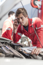Automechaniker mit Mobiltelefon in einer Reparaturwerkstatt - ZEF006976