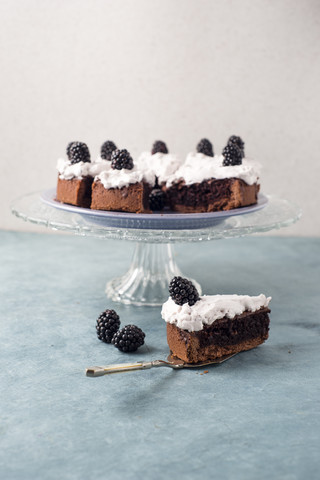 Sliced chocolate cake with creme and blackberries stock photo