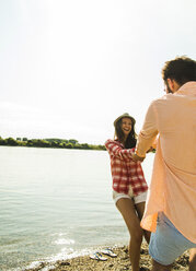 Carefree young couple hand in hand by the riverside - UUF005026