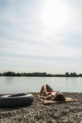 Junge Frau im Bikini beim Sonnenbaden am Flussufer - UUF005035