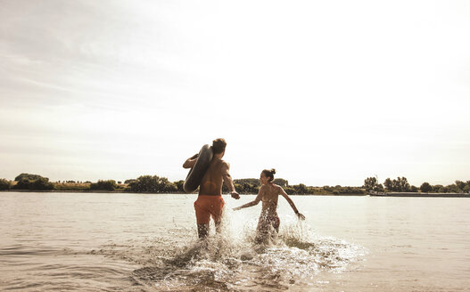 Junges Paar läuft mit Schlauch im Fluss - UUF005045