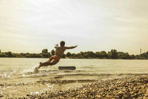 Junger Mann springt mit Schlauch in den Fluss - UUF005041