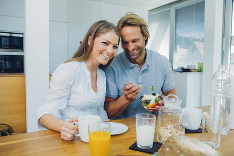 Glückliches Paar beim Essen am Küchentisch, lizenzfreies Stockfoto