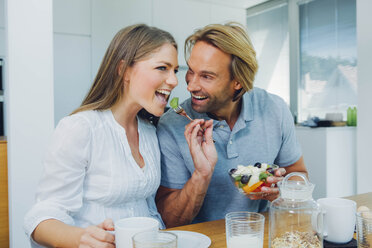 Happy couple eating at kitchen table - CHAF000861