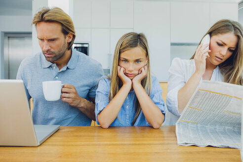 Frustrated girl with distracted parents at table - CHAF000969
