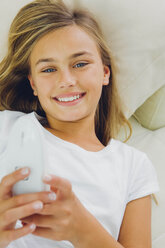 Portrait of smiling girl lying on couch - CHAF000881