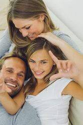 Happy father, mother and daughter relaxing on couch - CHAF000890