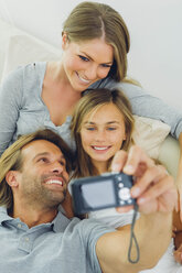 Glücklicher Vater, Mutter und Tochter machen ein Selfie auf der Couch - CHAF000891