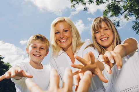 Porträt einer glücklichen Mutter mit ihren Kindern, die nach der Hand des Fotografen greifen, lizenzfreies Stockfoto