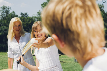 Teenager-Mädchen spielt Tennis mit ihrem Bruder, während ihre Mutter im Hintergrund steht - CHAF000903
