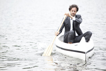 Germany, Rur Reservoir, businessman paddling in canoe - MFRF000254