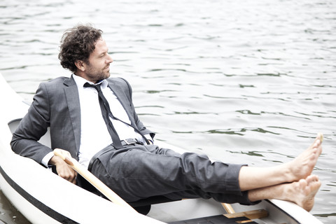 Germany, Rur Reservoir, businessman relaxing in canoe stock photo