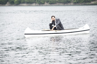 Germany, Rur Reservoir, businessman relaxing in canoe - MFRF000256