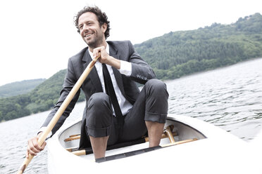 Germany, Rur Reservoir, smiling businessman in canoe - MFRF000258