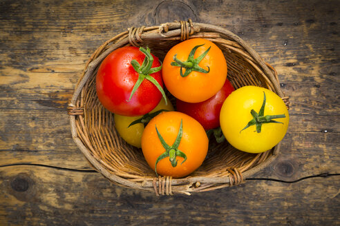 Weidenkorb mit verschiedenen Tomaten auf Holz - LVF003715