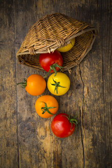 Weidenkorb und verschiedene Tomaten auf Holz - LVF003717