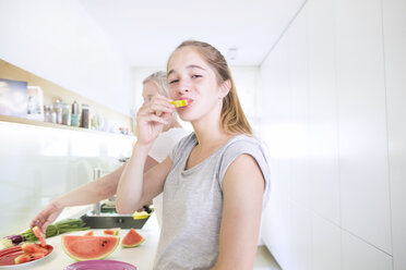 Porträt eines lächelnden Teenagers, der in der Küche Melone isst - SGF001796