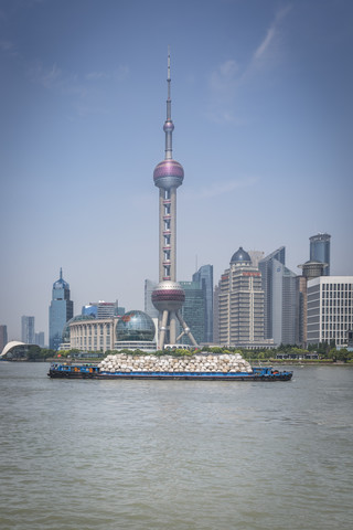 China, Shanghai, Oriental Pearl Tower und Frachtschiff auf dem Huangpu-Fluss, lizenzfreies Stockfoto