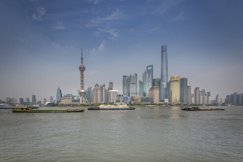 China, Shanghai, Skyline von Pudong mit Frachtschiffen auf dem Huangpu-Fluss - NKF000322