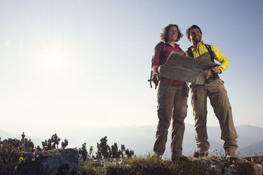 Austria, Tyrol, couple standing with map at Unterberghorn - RBF002978