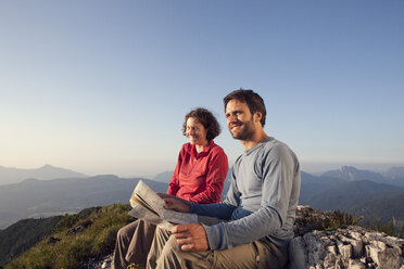 Austria, Tyrol, Unterberghorn, two hikers sitting with map in alpine landscape - RBF002981